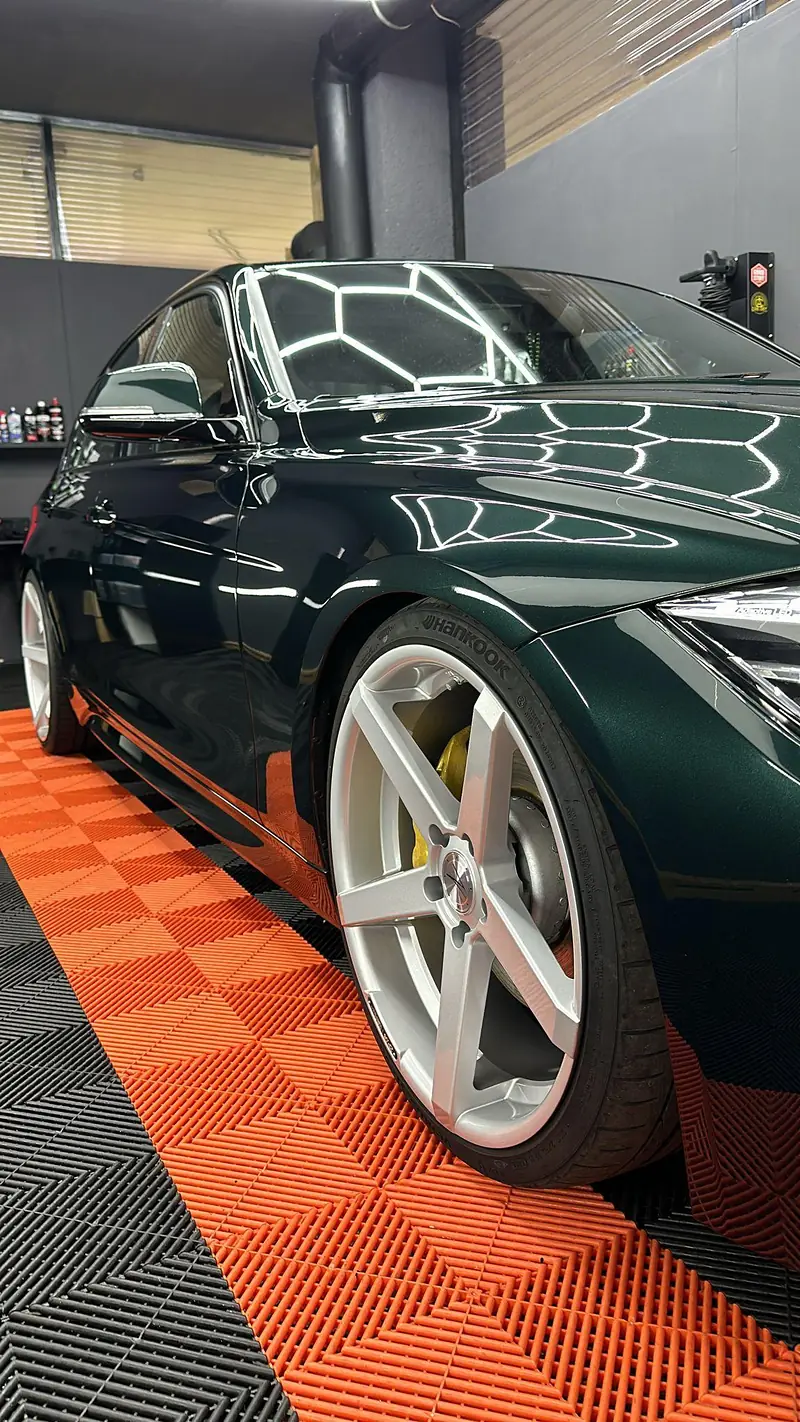 Dunkelgrünes Fahrzeug auf dem orangen Werkstattboden