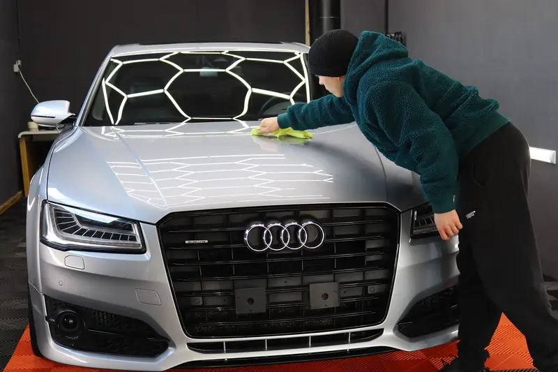 Keramikversiegelung wird von Hand auf die Motorhaube eines Audi S8 aufgetragen