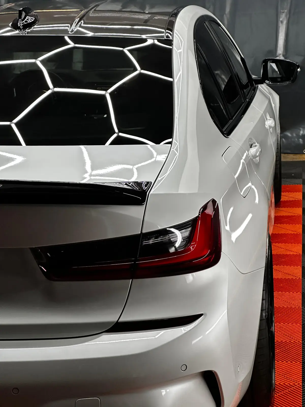 Weißer BMW 3er mit glänzendem Lack unter Hexagon-Licht in unserer Werkstatt