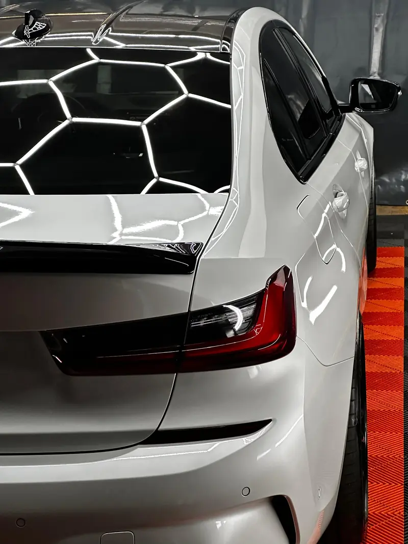Weißer BMW 3er mit glänzendem Lack unter Hexagon-Licht in unserer Werkstatt